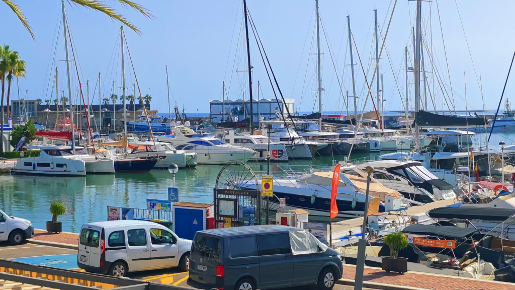 Sailboats and motorboats moored in Estepona Marina beside the harbour quay.