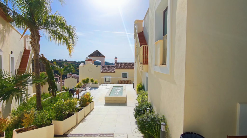 Landscaped walkway between cream-coloured residential buildings in Estepona.
